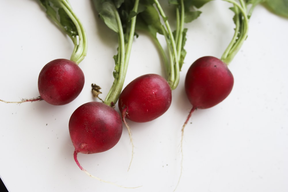 frutos rojos redondos sobre superficie blanca