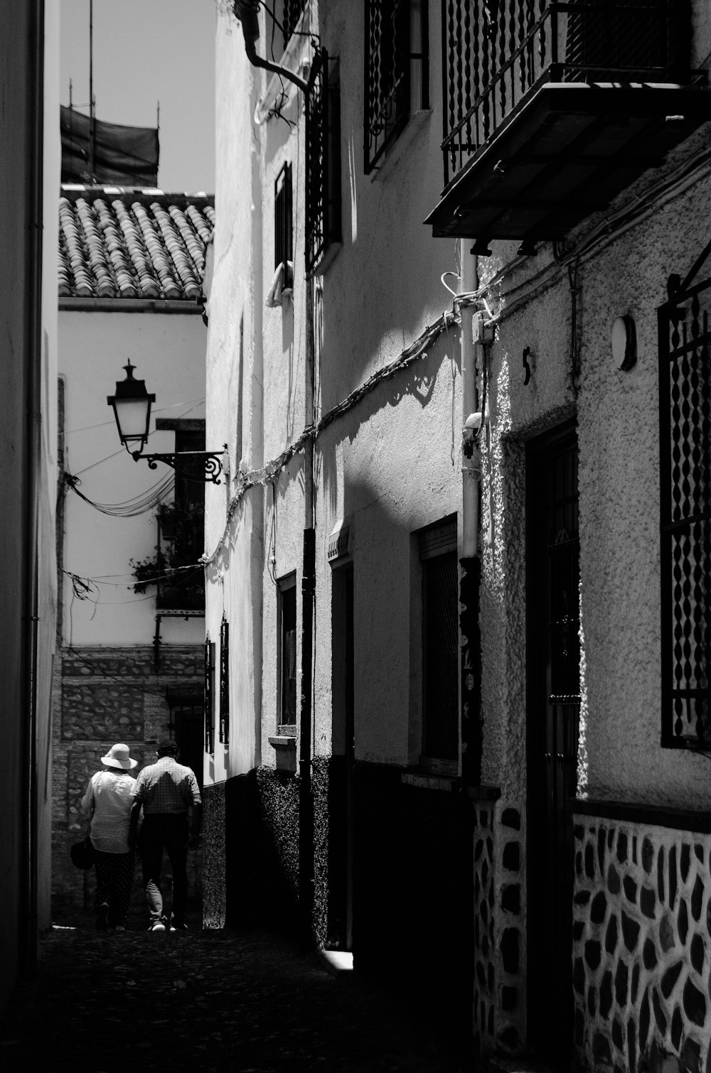 grayscale photo of woman in black jacket walking on street