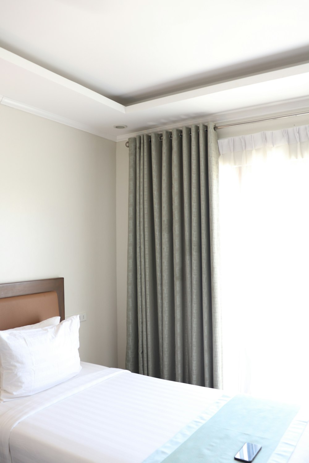 white bed linen near white window curtain
