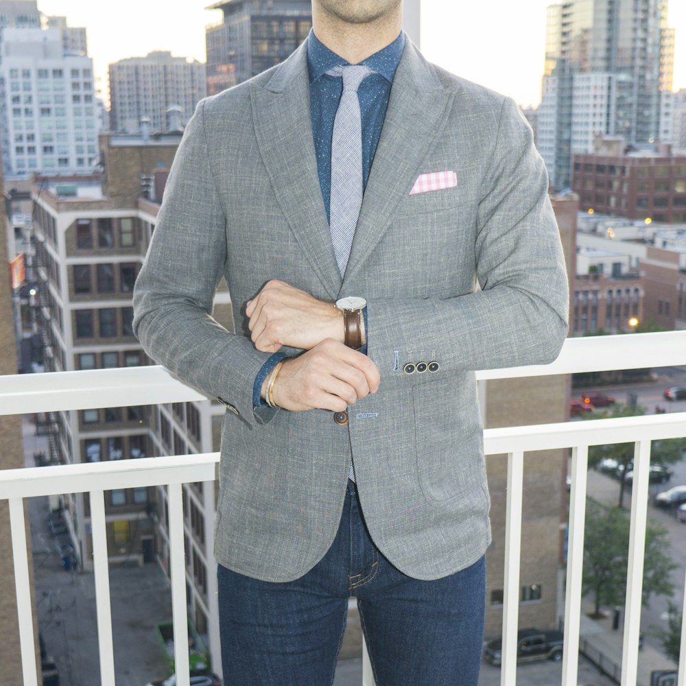 man in gray blazer standing near white wooden railings