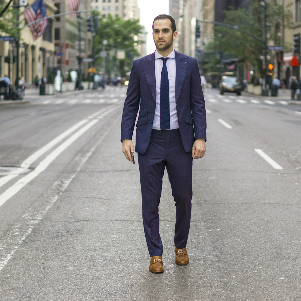 man in black suit standing on road during daytime