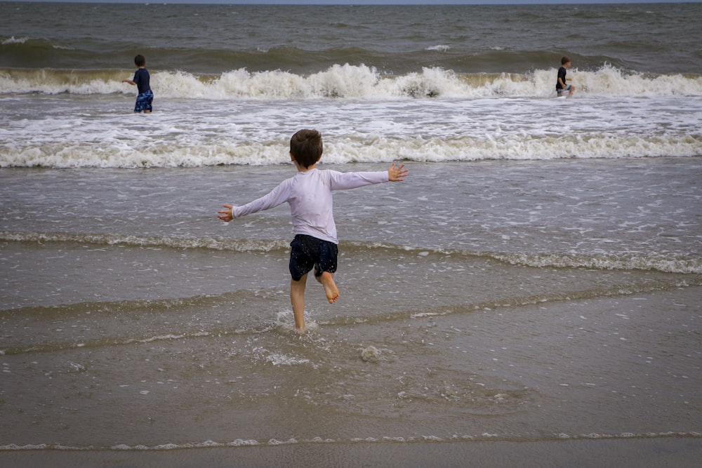 boy in red shirt and black shorts running on beach during daytime