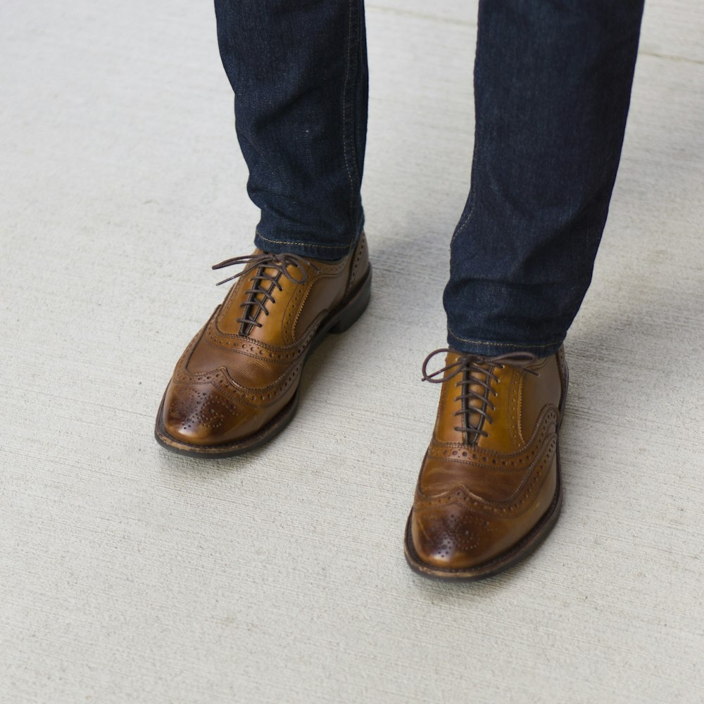 person in blue denim jeans and brown leather shoes