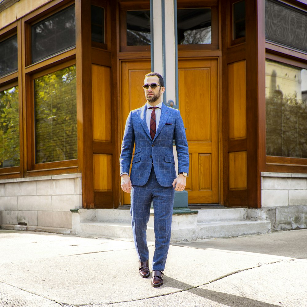 man in blue suit standing near brown wooden door