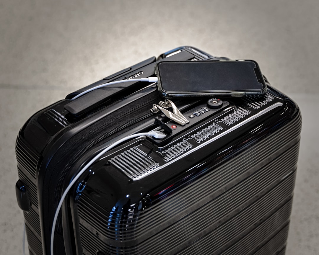 black and gray luggage bag, Charging an iPhone with a lightning cable that is connected to a carry-on suit case.