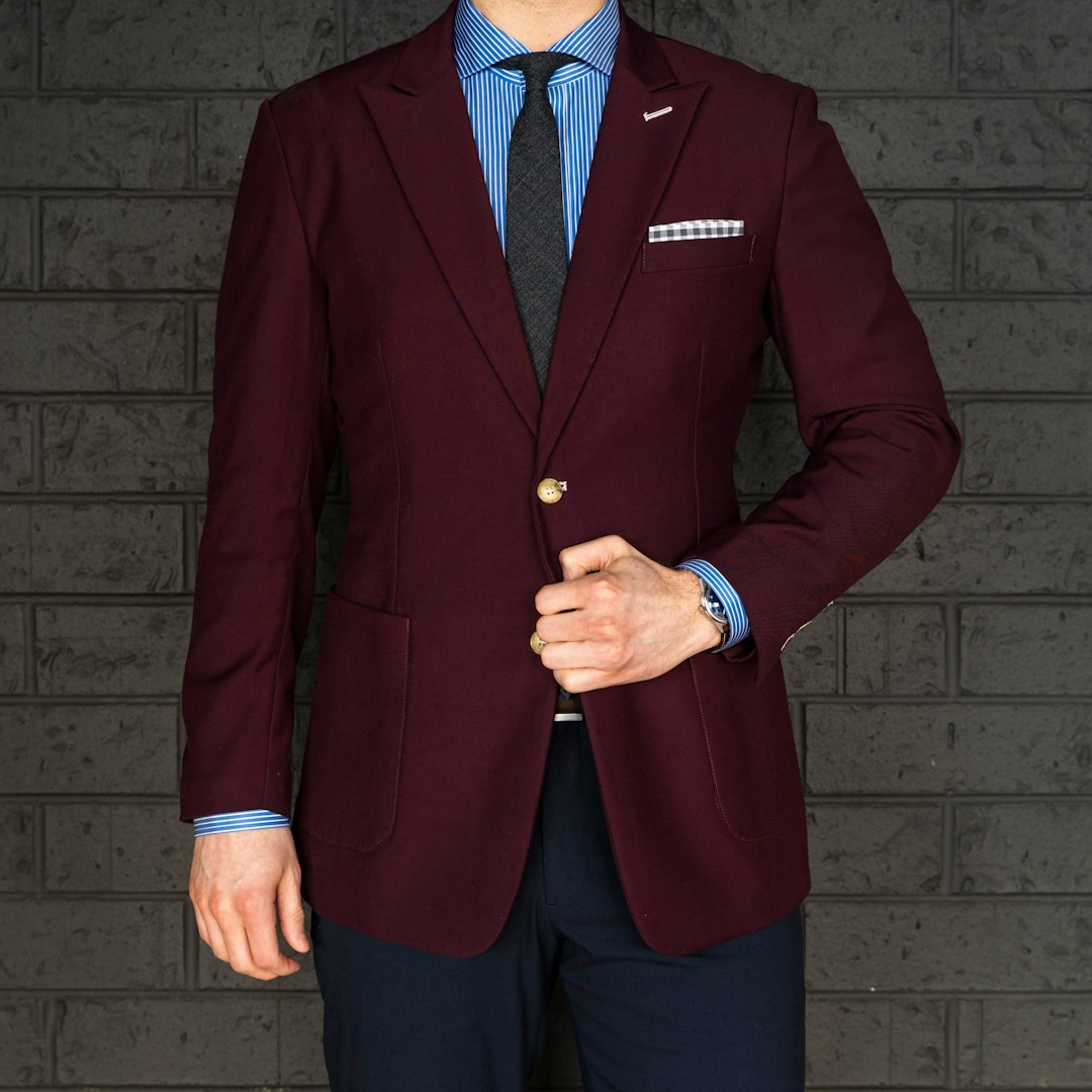 man in red suit jacket and blue dress pants