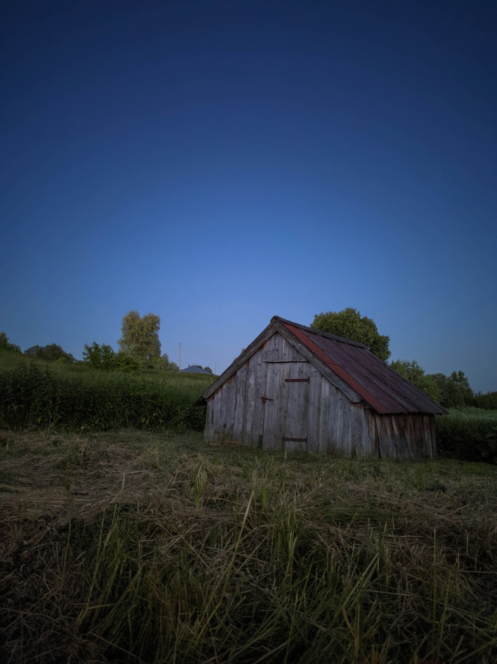 brown wooden house on green grass field under blue sky during daytime