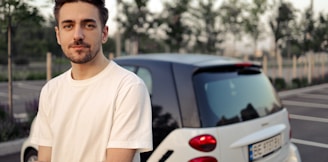 man in white crew neck t-shirt standing beside white car during daytime