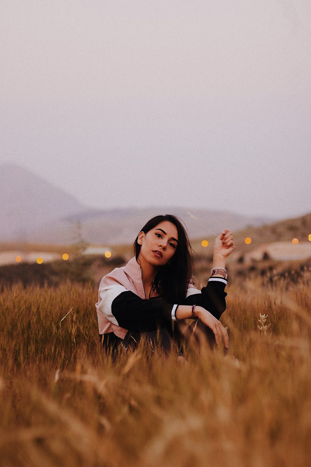 woman in black and white long sleeve shirt sitting on brown grass field during daytime