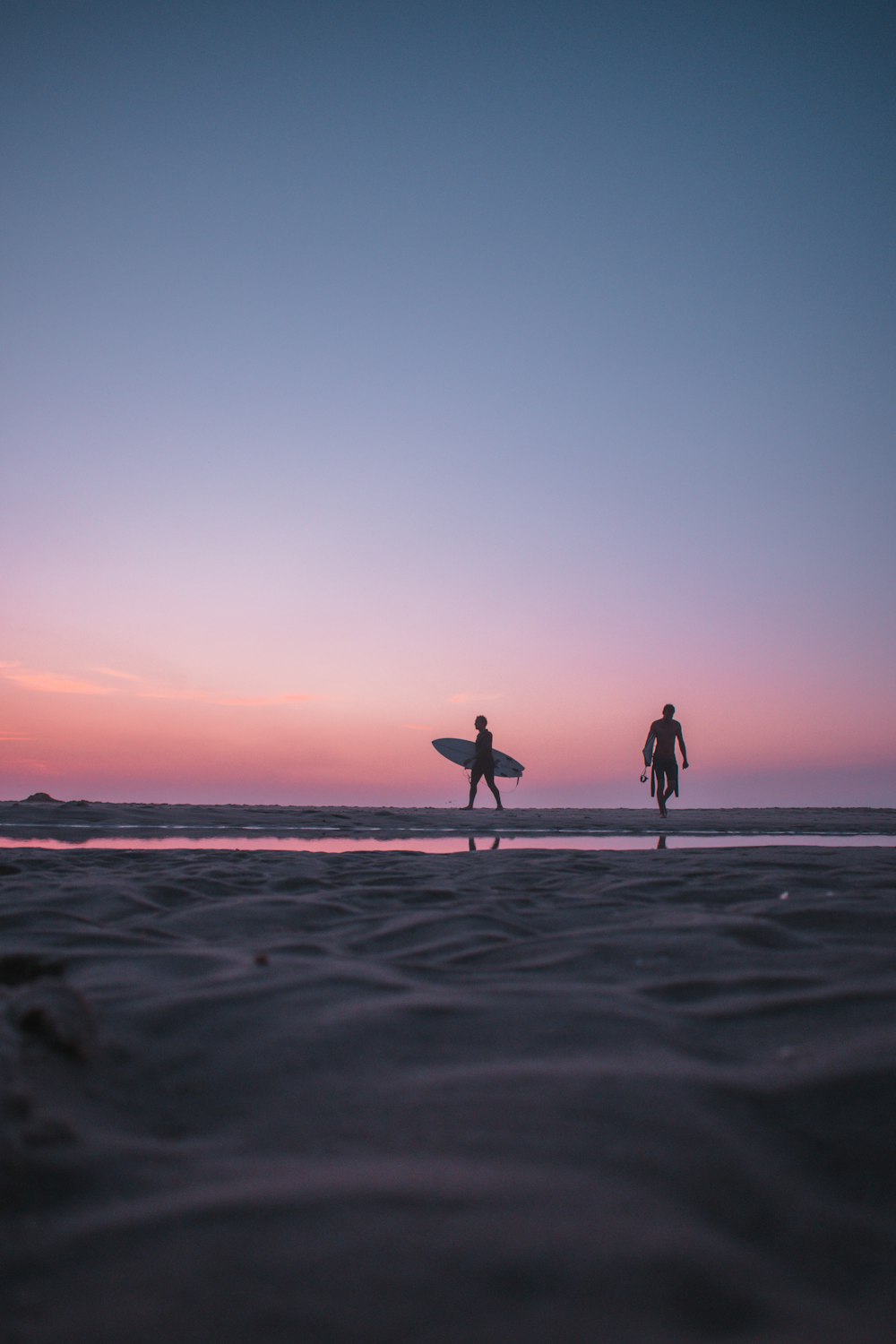 2 person walking on beach during sunset