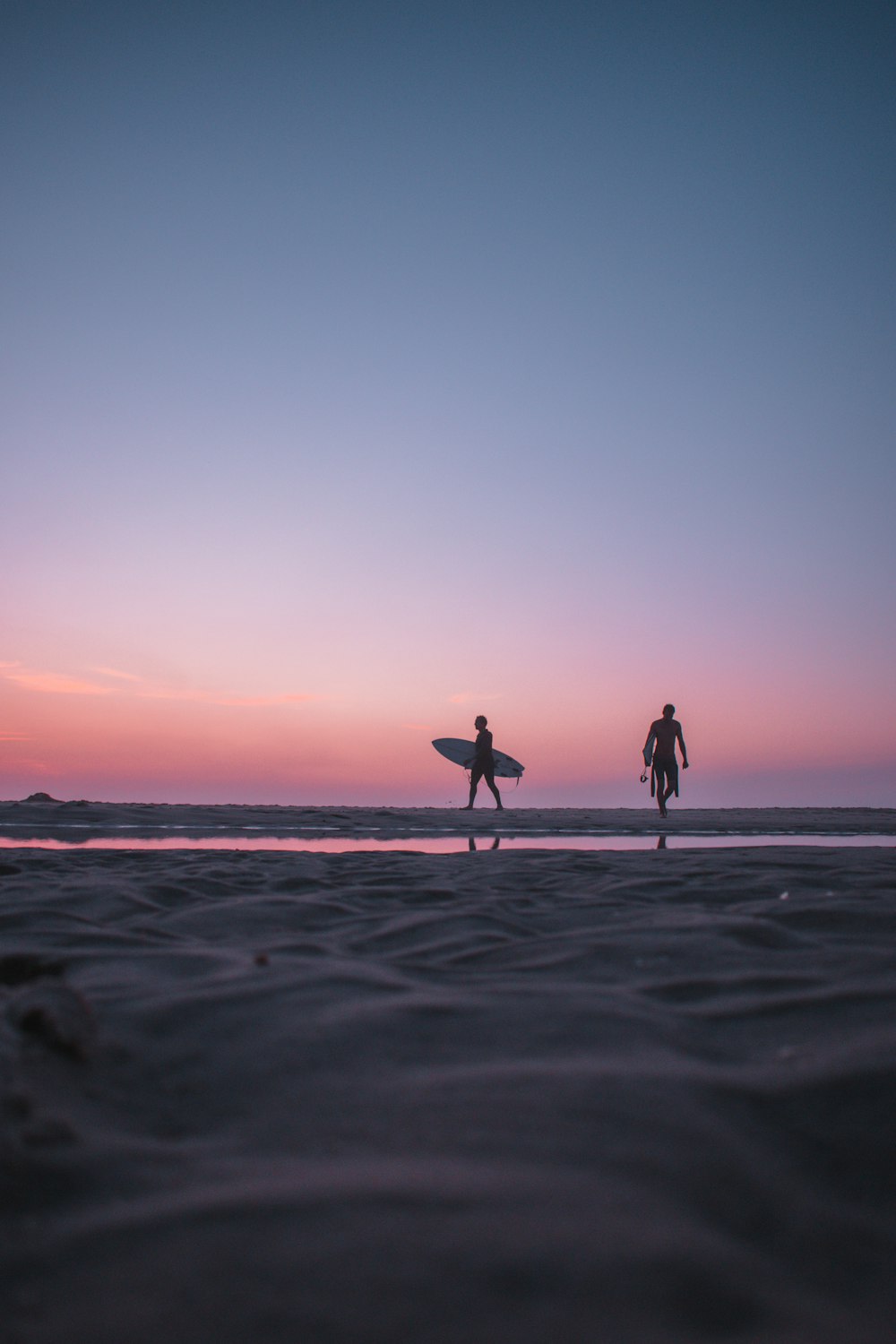 2 persone che camminano sulla spiaggia durante il tramonto