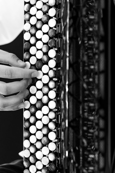 A close-up of hands skillfully playing a 31-button diatonic accordion.