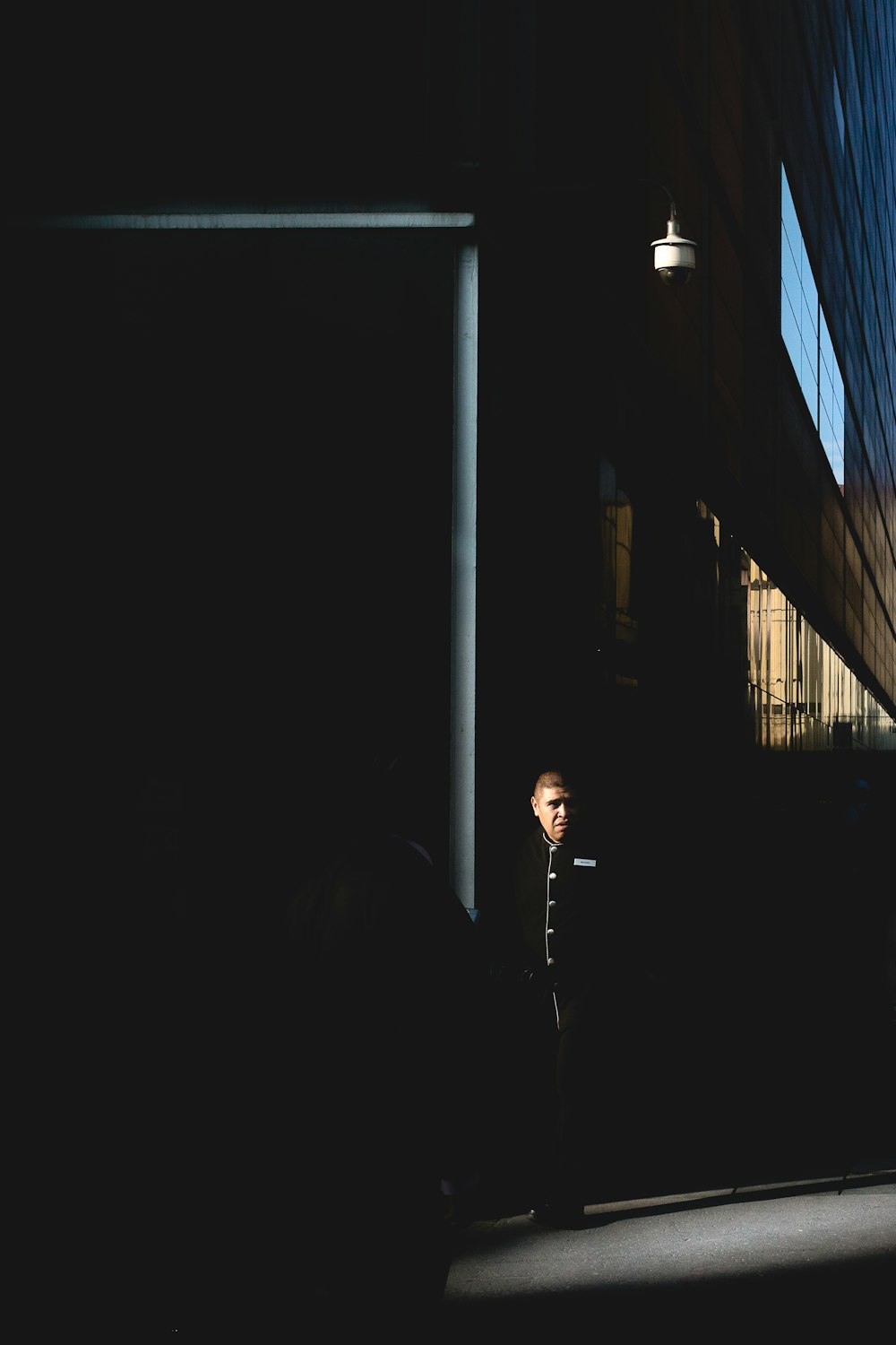 silhouette of man standing beside window during daytime