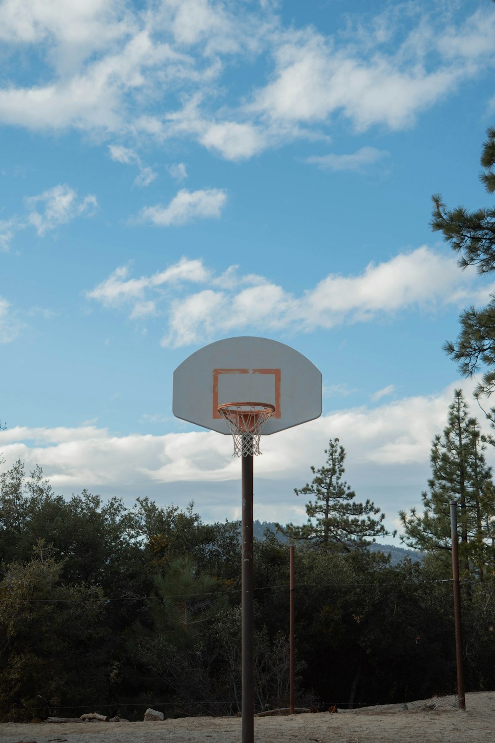 basketball hoop near trees under blue sky during daytime