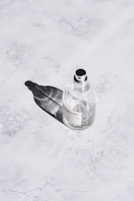 Close-up of a sleek perfume bottle resting on a marble surface with soft natural light.
