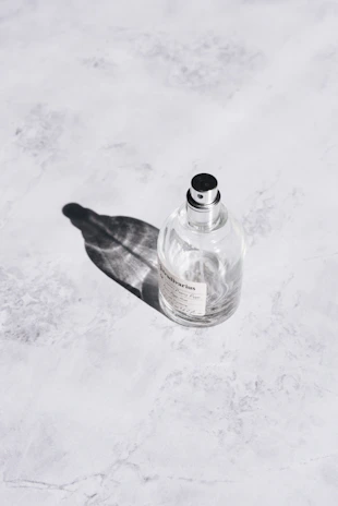 Close-up of a sleek perfume bottle resting on a marble surface with soft natural light.