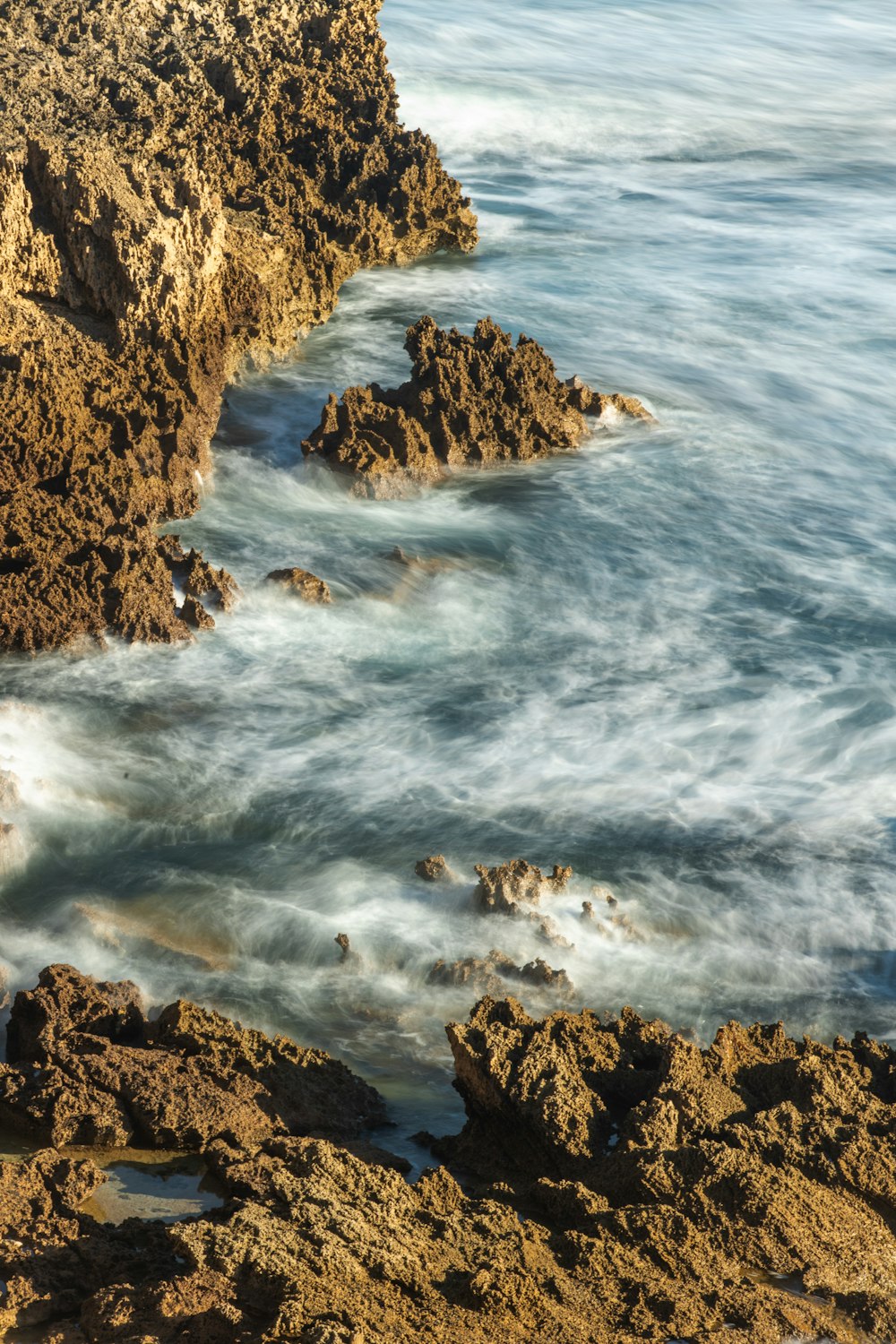 brown rocky mountain beside sea during daytime