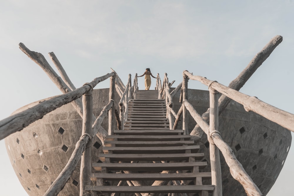 woman in black tank top and black pants walking on brown wooden stairs