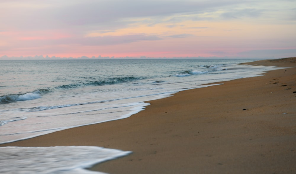 sea waves crashing on shore during sunset