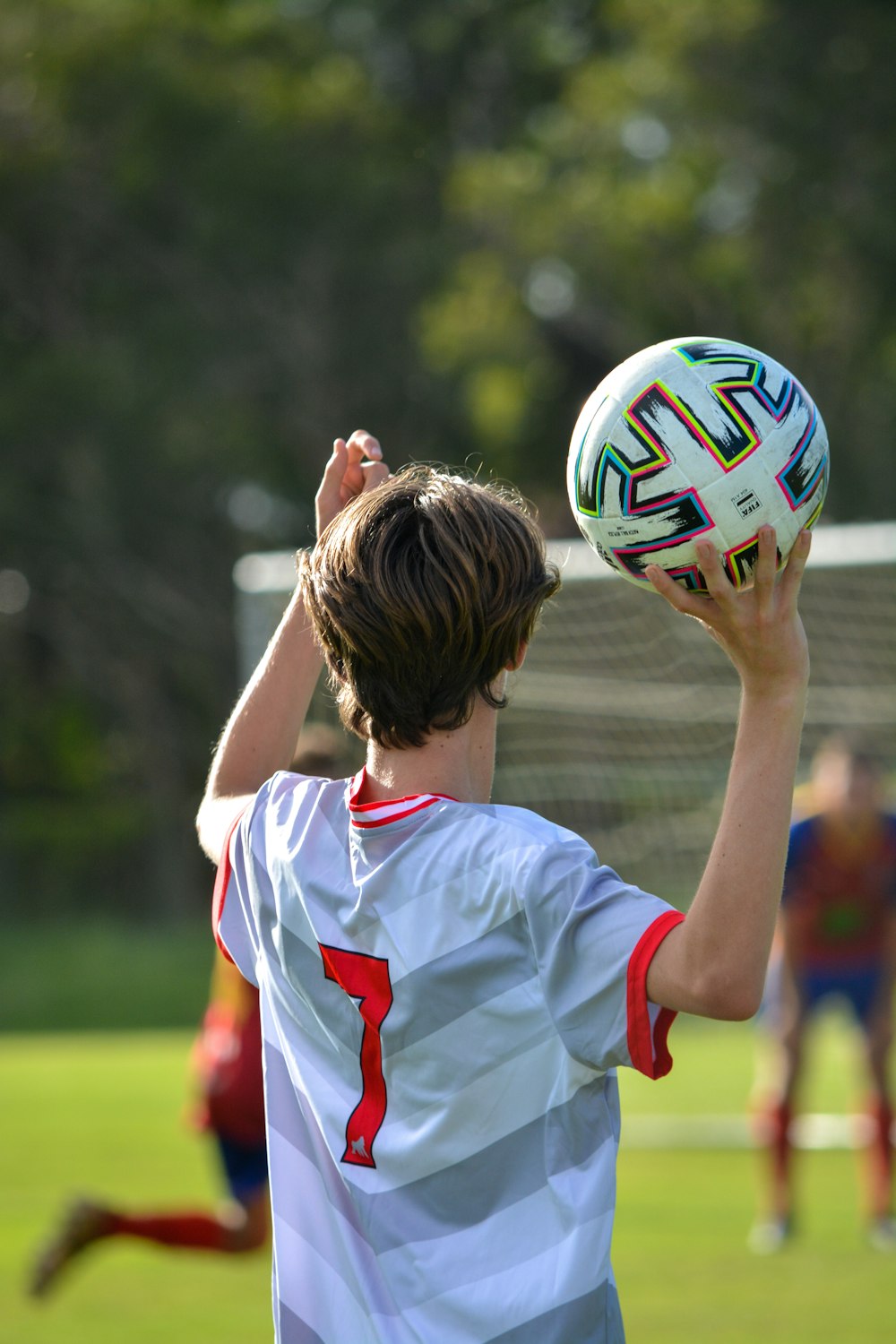 woman in white and red soccer jersey shirt holding white and blue soccer ball