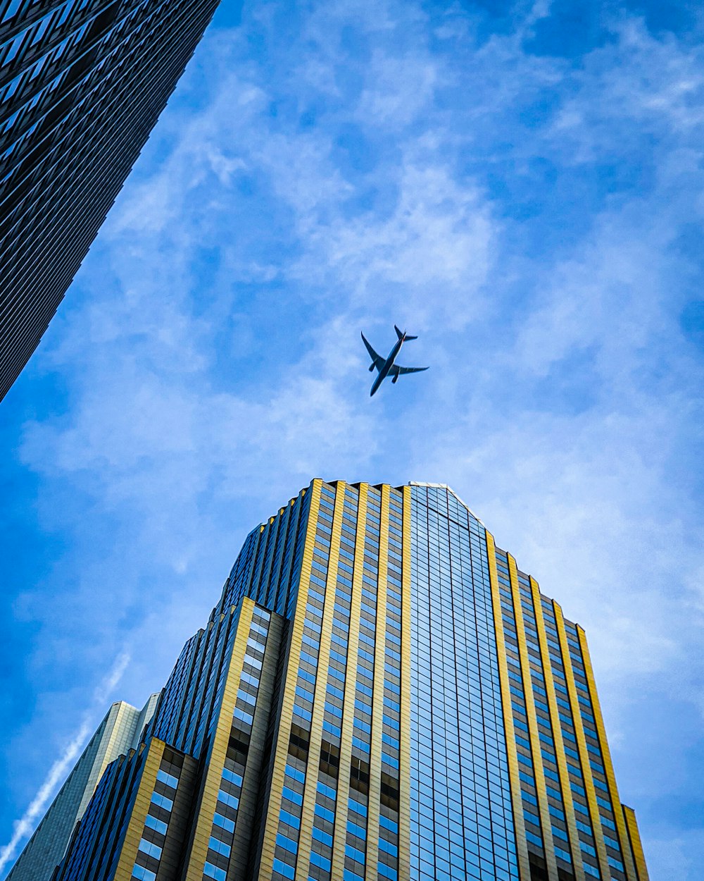 airplane flying over high rise building during daytime