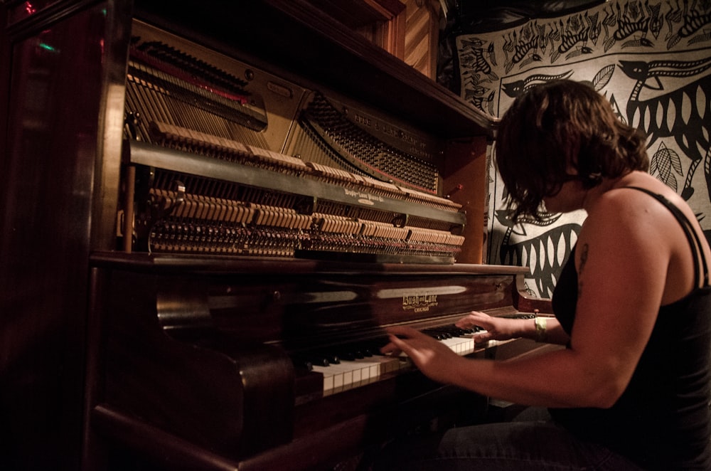 woman playing piano in grayscale photography