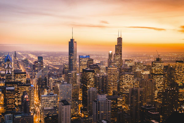 An inviting image of a bustling city skyline at sunset, with lights beginning to twinkle.