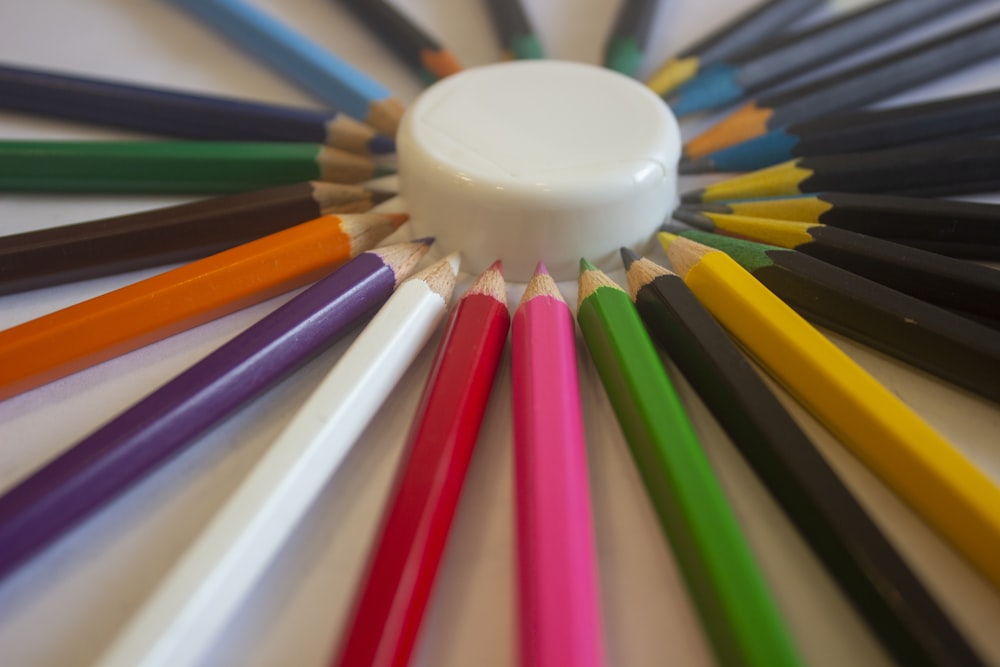 色とりどりの色鉛筆に白い丸いプラスチック容器