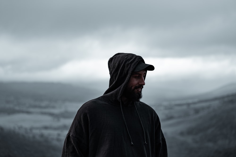 man in black hoodie standing near body of water during daytime