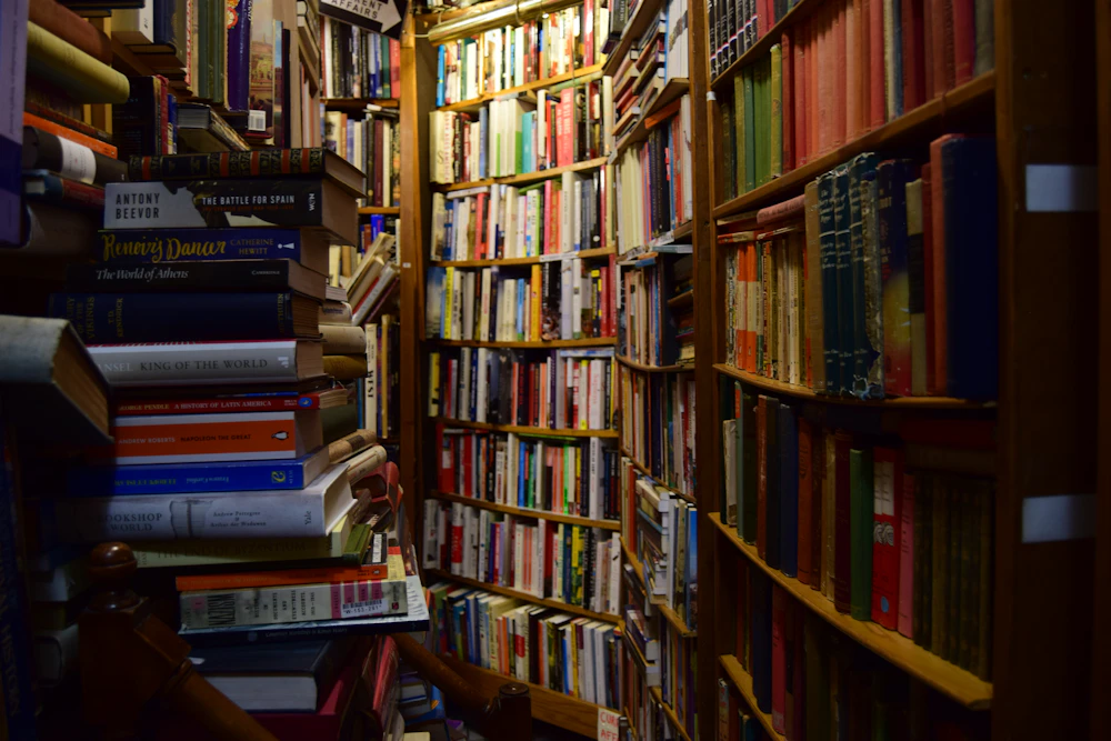 Pasillo angosto de una librería con estanterías repletas de libros hasta el techo