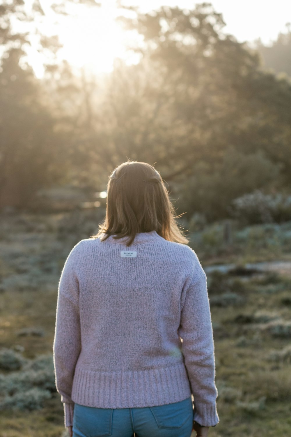 woman in gray sweater standing on brown field during daytime