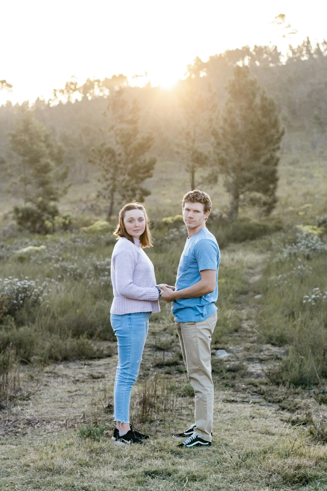 woman in white long sleeve shirt and blue denim jeans standing on green grass during daytime