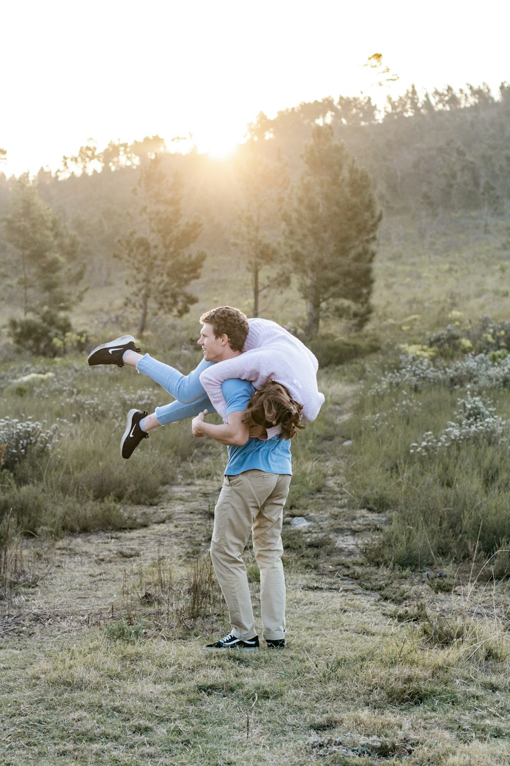 man in white shirt carrying woman in blue jacket during daytime