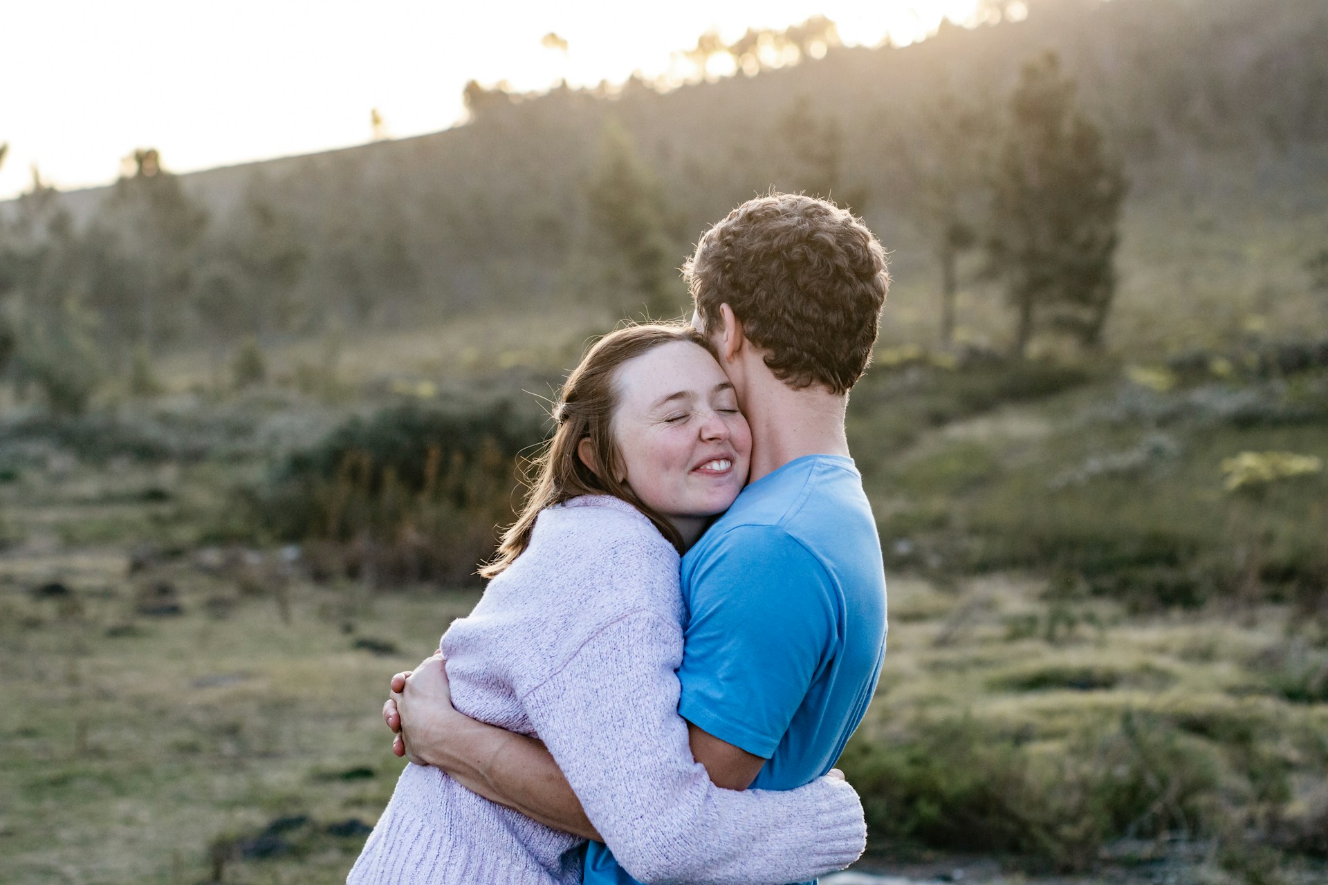 A serene outdoor setting with a couple embracing during sunset, capturing a moment of love and connection.