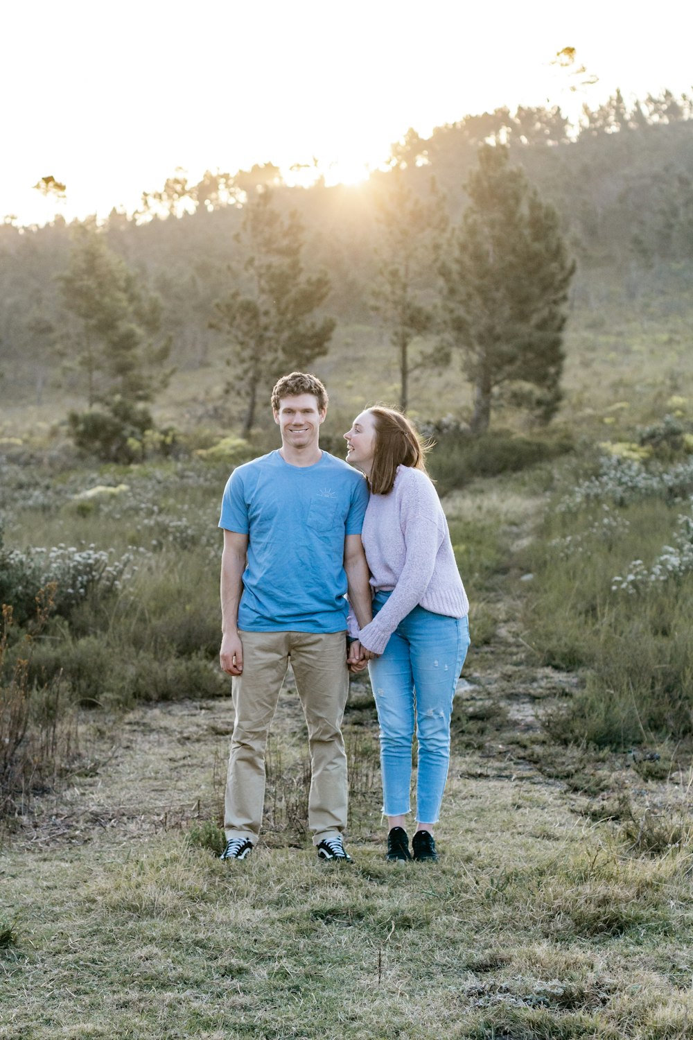 man and woman holding hands while walking on green grass field during daytime