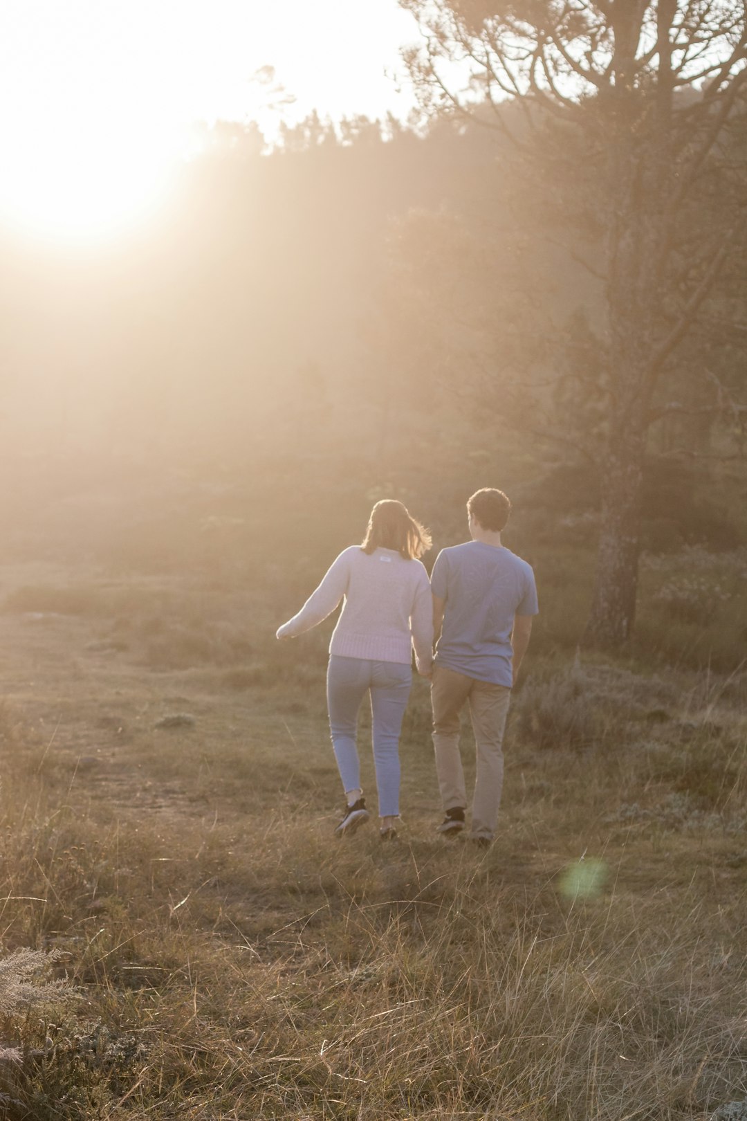 man and woman walking on grass field during daytime