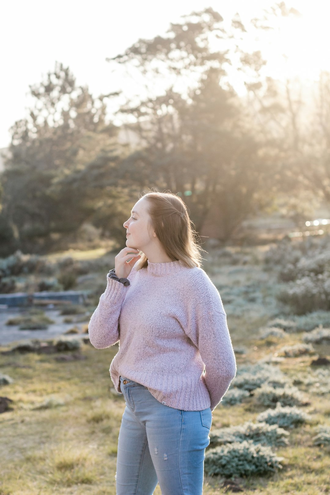 woman in white sweater standing near river during daytime