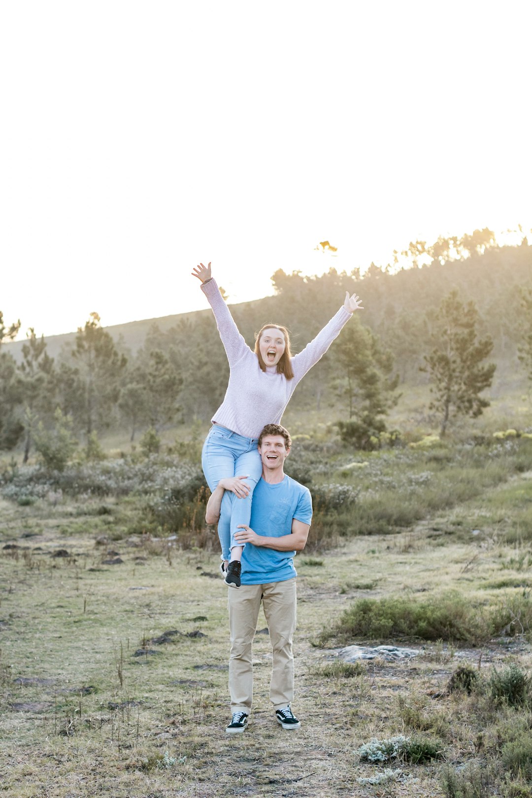 woman in blue tank top and gray pants raising her hands