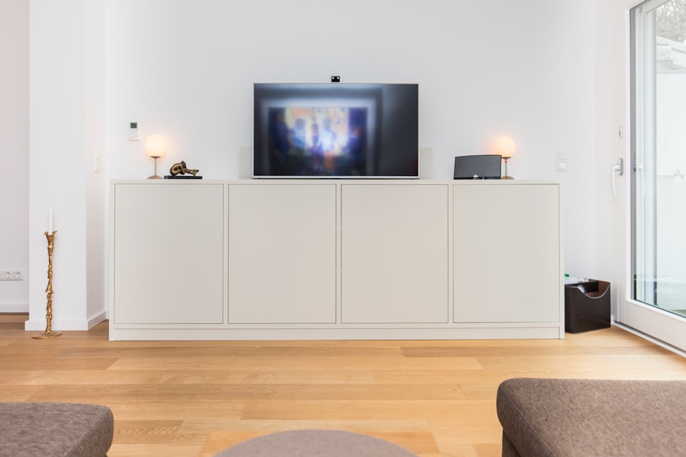 black flat screen tv turned on on white wooden tv hutch