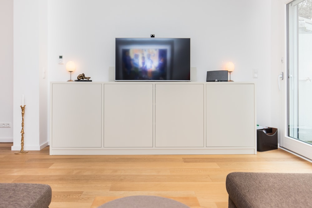 Televisor de pantalla plana negro encendido en una conejera de madera blanca
