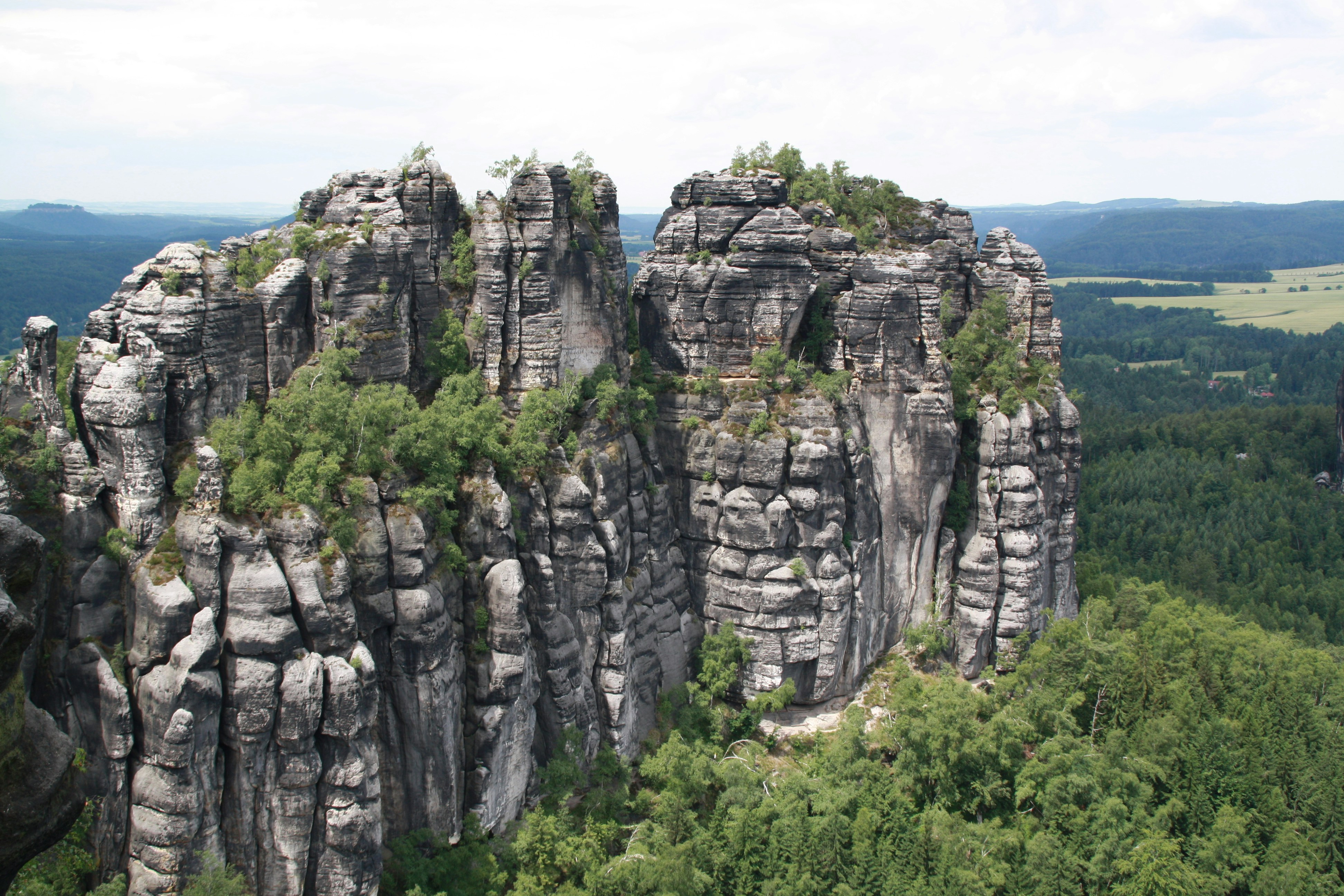 gray rocky mountain near green trees during daytime