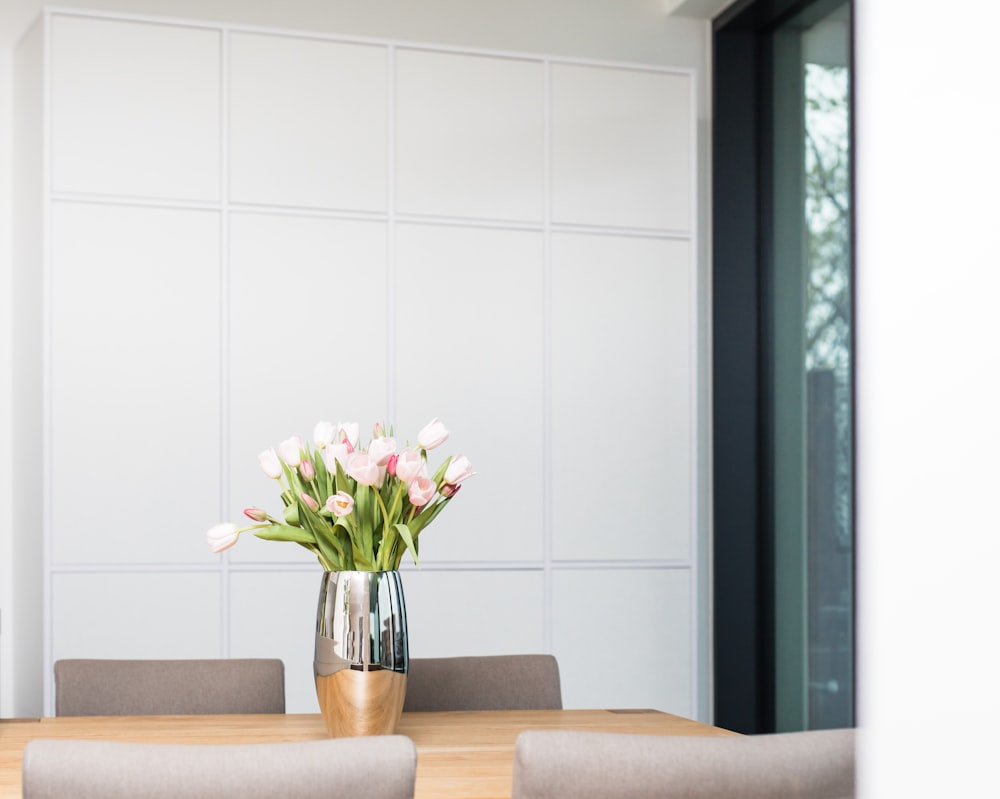 white and pink flowers in clear glass vase on brown wooden table