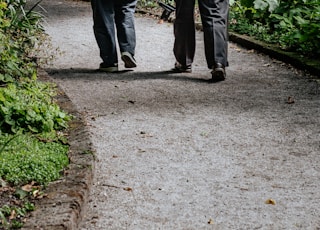 man in white shirt and blue denim jeans walking on pathway