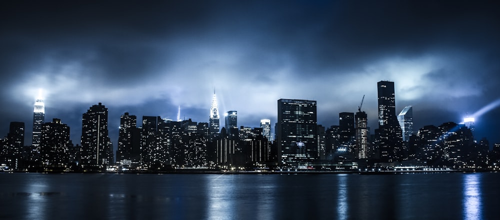 city skyline across body of water during night time