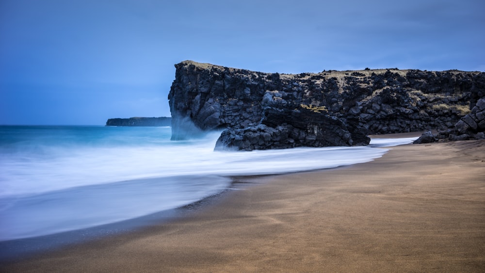 ocean waves crashing on brown rocky shore during daytime