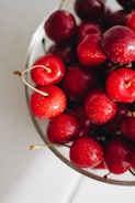 A bowl filled with bright red cherries, glistening with freshness.