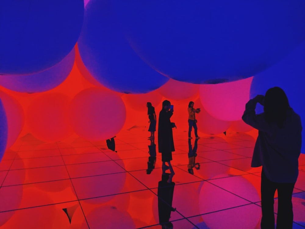 silhouette of people standing on blue and red balloons