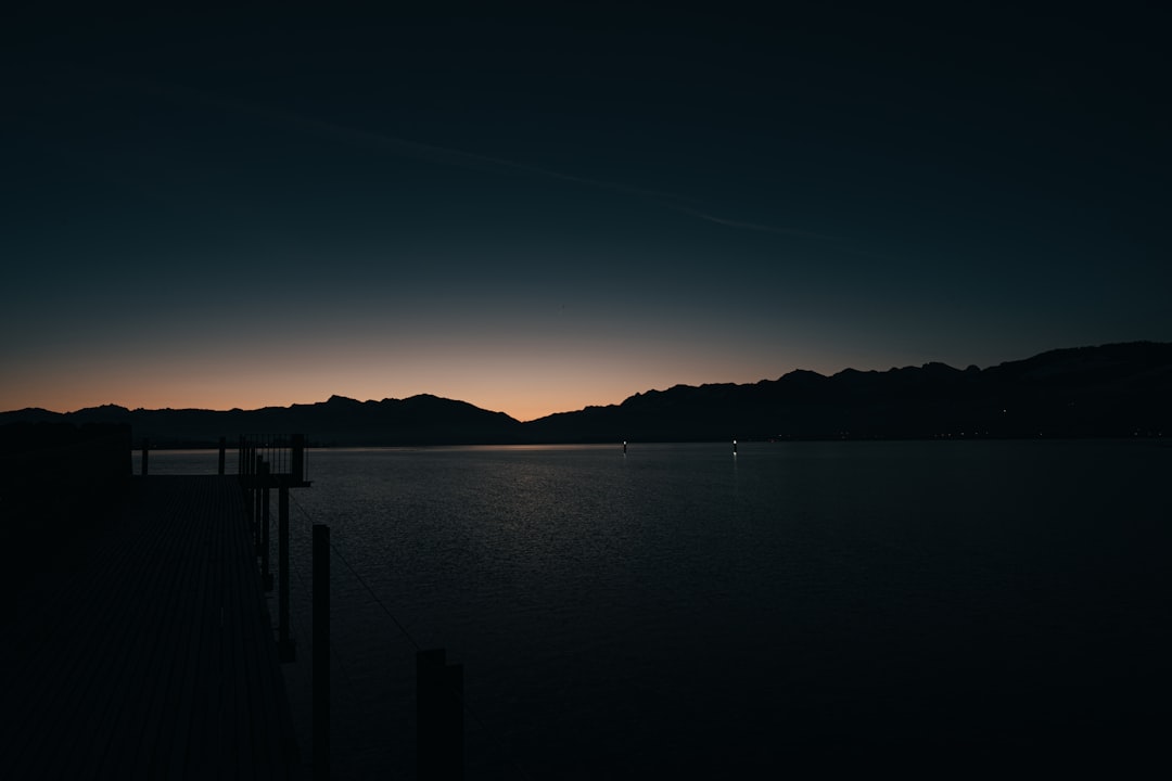 silhouette of dock on calm water during night time