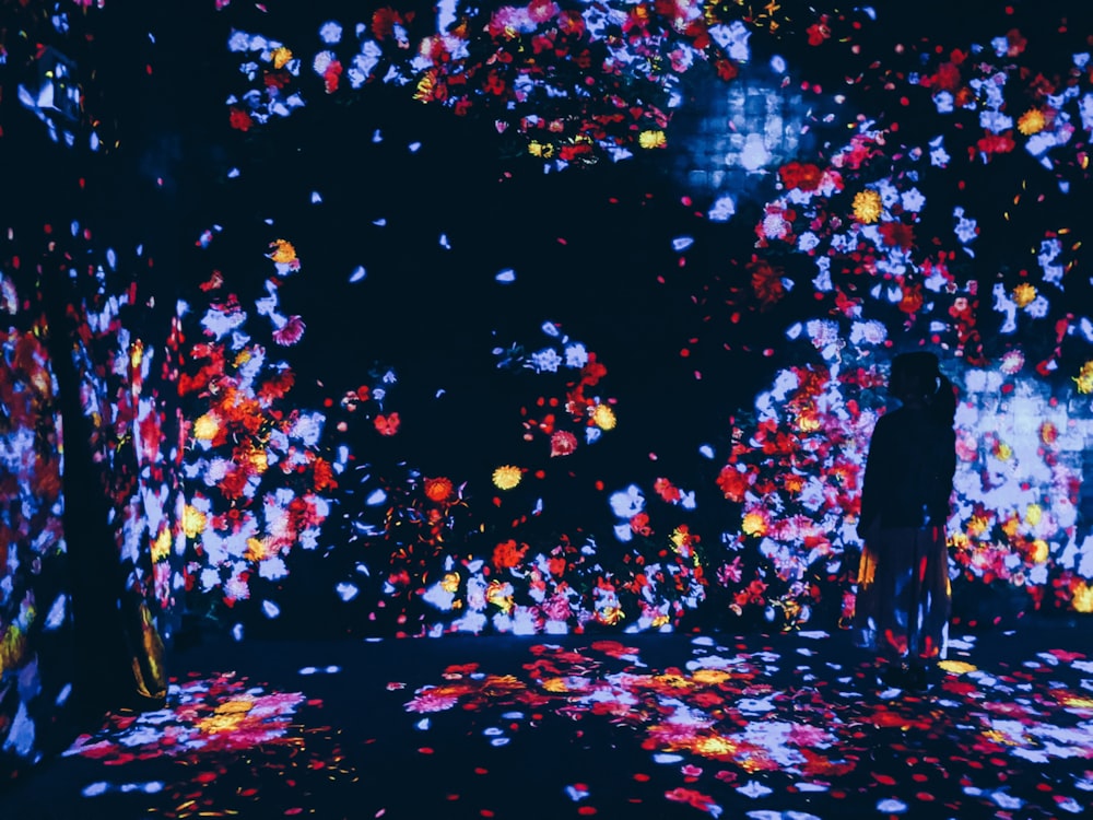 man in black jacket standing under pink and white string lights