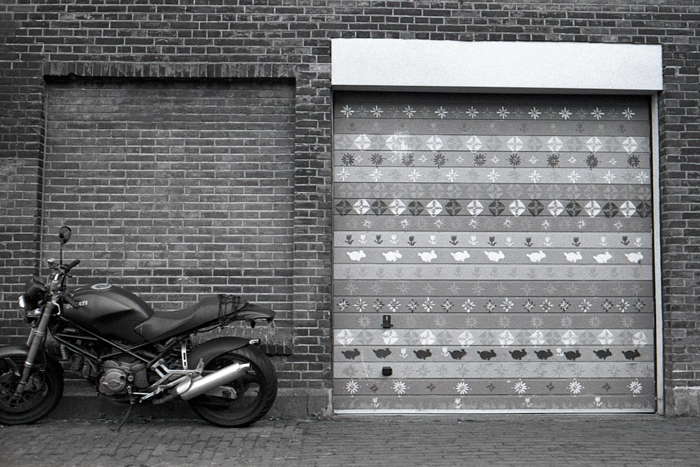 black motorcycle parked beside blue and white brick wall